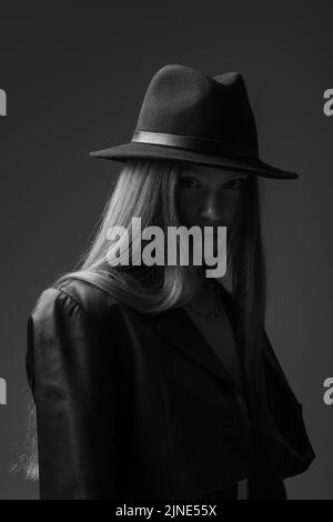 photo monochrome du mannequin adolescent dans le chapeau fedora regardant l'appareil photo en studio Banque D'Images