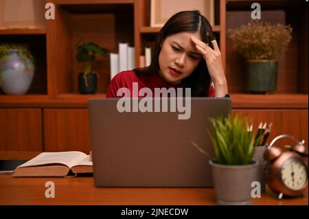 Une jeune femme d'affaires asiatique stressée et sérieuse ou une femme directrice a un problème d'ordinateur portable ou un problème d'affaires. Banque D'Images