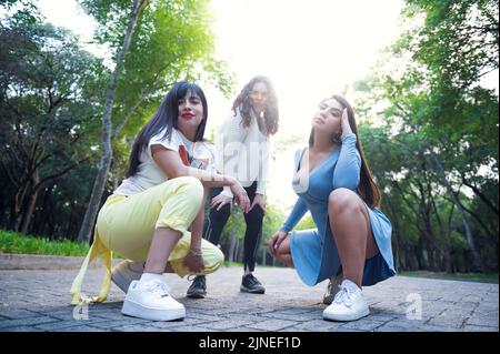 Trois amies posant et prenant des photos dans un parc Banque D'Images