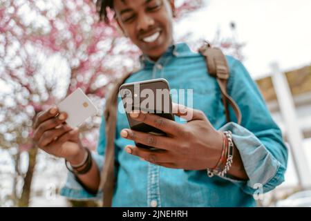 Guy tenant la carte regardant joyeusement l'écran de smartphone Banque D'Images