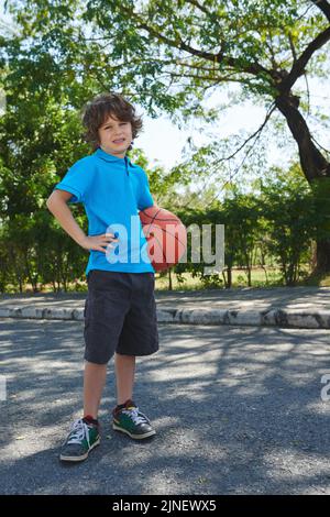 Gamin joyeux avec ballon de basket-ball jouant à l'extérieur Banque D'Images