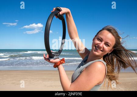 femme avec pilates anneau sur la plage Banque D'Images