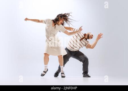 Rythme et expression. Couple de danse énergique dans des tenues de style rétro dansant lindy hop, jive isolé sur fond blanc. 50s, 60s, 70s américain Banque D'Images