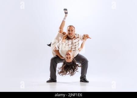 Rythme et expression. Couple de danse énergique dans des tenues de style rétro dansant lindy hop, jive isolé sur fond blanc. 50s, 60s, 70s américain Banque D'Images