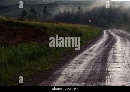 Une route qui serpente à travers la vallée de Kamberg en Afrique du Sud dans les montagnes de Drakensberg après une pluie hivernale Banque D'Images