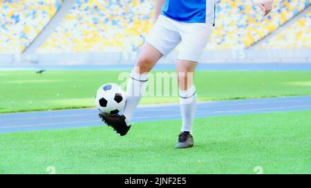 vue rognée du joueur de football dans un short rebondissant le ballon de football avec les jambes, image de stock Banque D'Images
