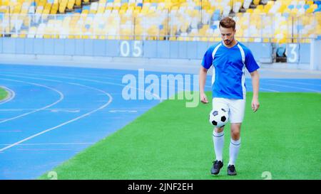 jeune et sportif joueur de football rebondissant ballon de football avec des jambes, image de stock Banque D'Images