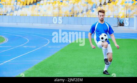 jeune joueur de football rebondissant ballon de football avec des jambes sur le stade, image de stock Banque D'Images