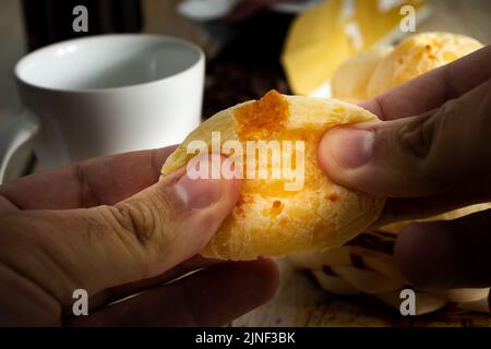 mains ouvrant un pain de fromage en deux Banque D'Images