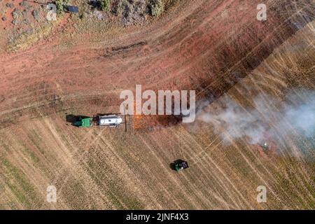 Un tracteur tirant un brûleur de propane brûle les mauvaises herbes dans un champ de foin après avoir coupé la luzerne dans un ranch de l'Utah. Banque D'Images