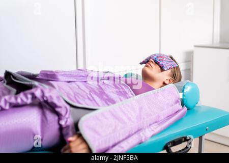 Femme couché avec les yeux fermés pendant la séance de pressothérapie dans la clinique de beauté. Concept Banque D'Images