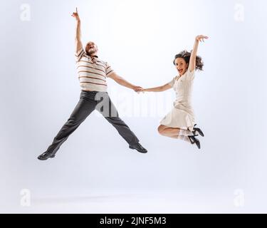 Étonnant jeune dansant homme et femme danse sport danses isolées sur fond blanc. 50s, 60s, 70s style de mode américain. Banque D'Images