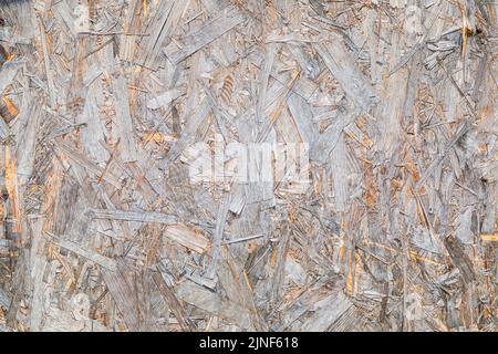 La texture du matériau OSB est un panneau fabriqué à partir de copeaux de bois pressés recyclés. Panneaux de particules provenant de grands déchets de bois. Gros plan. Banque D'Images