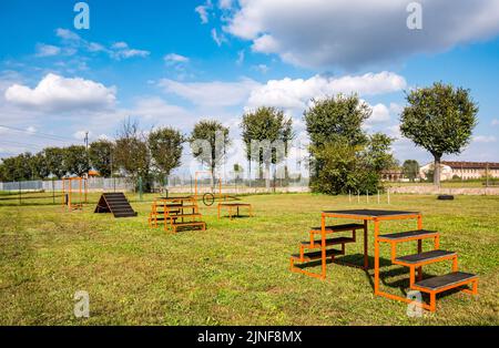 Zone équipée pour l'entraînement des chiens. Dressage de chiens dans une zone clôturée. Parcours d'obstacles avec tunnels, rampe raide, toboggans, poteaux et saut en hauteur. Vue horizontale Banque D'Images