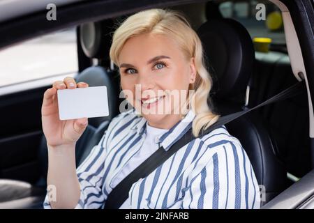 Femme joyeuse titulaire d'un permis de conduire en voiture, image de stock Banque D'Images