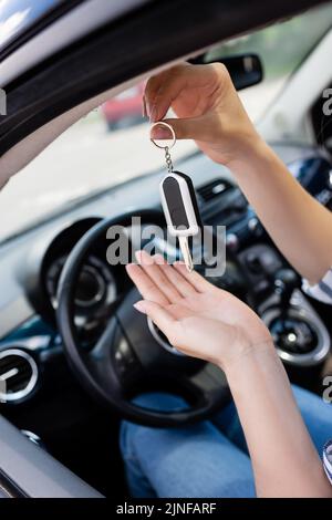 Vue rognée de la femme tenant la clé tout en étant assise sur le siège du conducteur dans la voiture, image de stock Banque D'Images