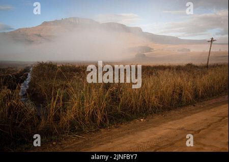La brume est brûlée par le soleil révélant le Mont Erskine au-dessus de la vallée de Kamberg dans les montagnes de Drakensberg en Afrique du Sud Banque D'Images