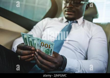 Recalcul de l'argent papier gagné. Gros plan des mains d'un homme comptant des billets en dollars. Le concept d'une transaction parfaite et de rentabilité de l'entreprise Banque D'Images