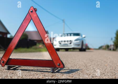 Concept de panne de voiture. Gros plan du triangle d'arrêt d'avertissement sur l'arrière-plan de la voiture Banque D'Images