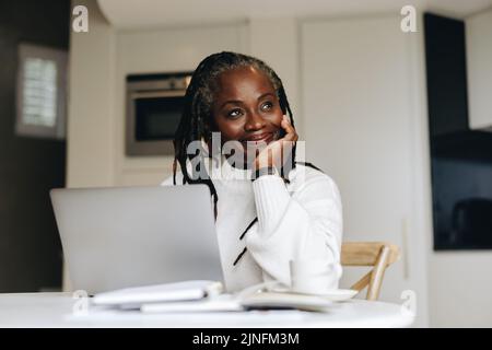 Une femme d'affaires enjouée d'une bonne humeur en travaillant sur un ordinateur portable à la maison. Femme d'affaires mature qui fait du travail indépendant en ligne dans son cdm Banque D'Images
