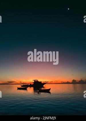 Magnifique coucher de soleil orange sur yacht et petits bateaux en mer. Le ciel coloré se reflète sur la surface lisse de l'eau Banque D'Images
