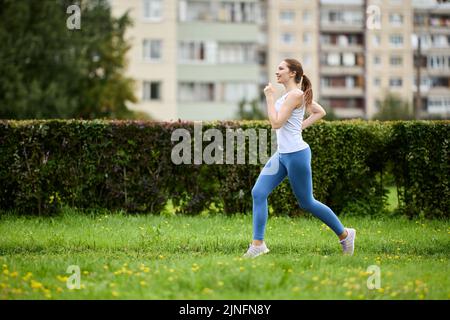 Une jeune femme en leggings et débardeur fait la course du matin. Banque D'Images
