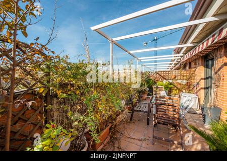 Terrasse avec supports en aluminium blanc pour auvents coulissants, murs de briques et beaucoup de plantes Banque D'Images