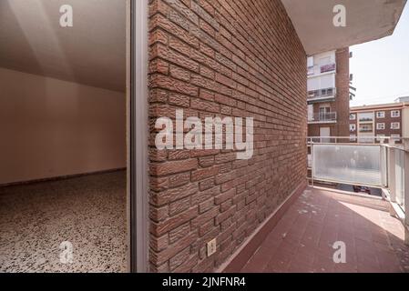 Petite terrasse vide avec briques apparentes, sols en argile et balustrade en métal et verre translucide Banque D'Images