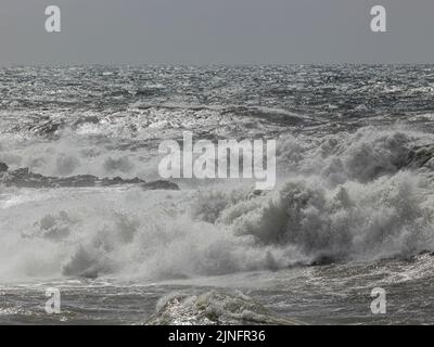 Paysage marin orageux avec vagues de rupture contre des rochers au premier plan Banque D'Images