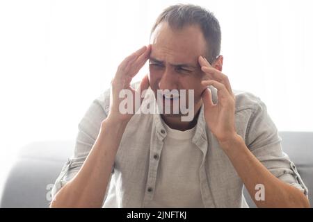 Exténué travailleur du millénaire caucasien prendre des lunettes de massage les yeux souffrent de maux de tête ou de migraine, l'homme fatigué se sentent la fatigue submergée par Banque D'Images