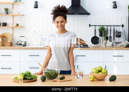 Alimentation saine alimentation afro-américaine jeune femme préparant une salade dans la cuisine maison femme cuisinant une nourriture saine Banque D'Images