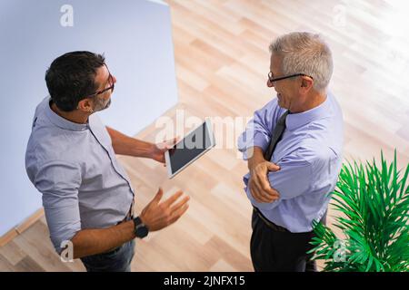 Deux hommes d'affaires principaux parlent et rient, grand ange Banque D'Images