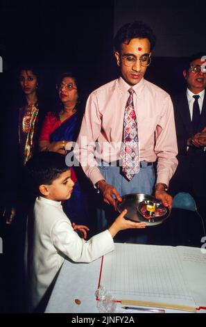 Père et fils tenant Diya sur Red Chopdis exécutant Chopda Puja pendant Diwali signifiant le début de la nouvelle année financière dans l'Hindu Calenda Banque D'Images