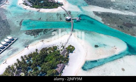 Vue aérienne de l'île entourée d'eau émeraude avec bungalows sur la côte de l'océan dans la station Maldives Banque D'Images