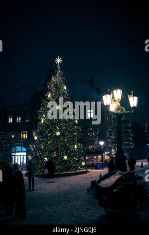 Lund, Suède - 10 décembre 2021 : les gens admirent l'arbre de noël lumineux sur la place principale pendant que la neige tombe Banque D'Images