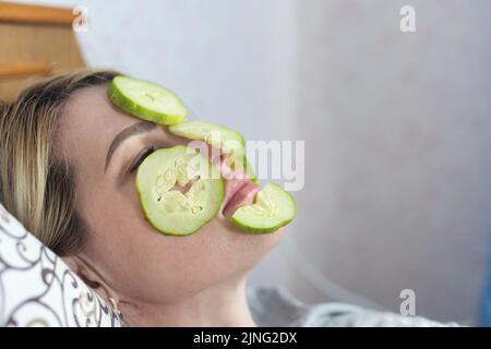 Jeune belle femme avec un paquet de visage et des tranches de concombre frais sur ses yeux. Masque de boue maison à la maison. Multani sol visage-pack, or visage Banque D'Images