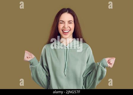 Une jeune femme heureuse avec un sourire joyeux se réjouit sincèrement des nouvelles positives ou du cadeau d'anniversaire. Banque D'Images