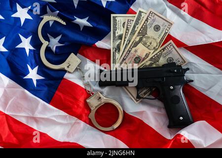 Menottes de police, dollars et une arme sur le drapeau des États-Unis, gros plan Banque D'Images