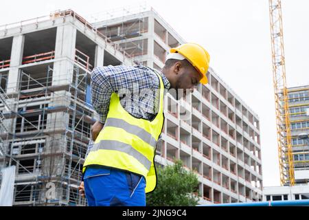 Ingénieur souffrant de douleurs dorsales après un accident sur le chantier de construction Banque D'Images