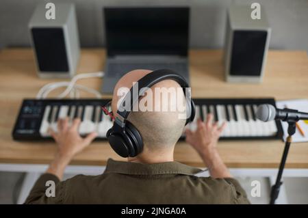 Un musicien de sexe masculin dans un écouteur compose de la musique sur un clavier Banque D'Images