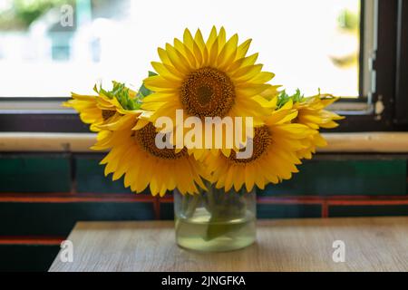 Un beau bouquet de tournesols dans un vase en verre sur la fenêtre. Banque D'Images