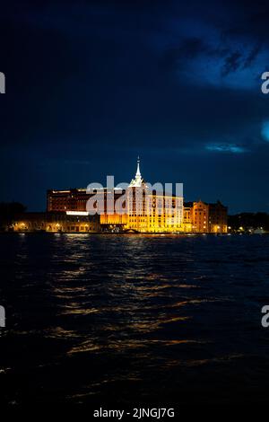 Une photo verticale du Hilton Molino Stucky Venice illuminé par la lumière la nuit Banque D'Images