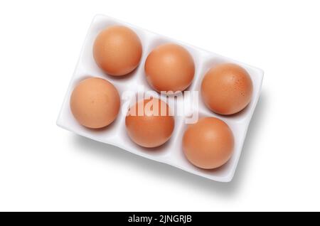 Une demi-douzaine ou six œufs de poules dans un plateau en céramique blanc ou un support tiré du dessus isolé sur du blanc avec découpe du chemin Banque D'Images