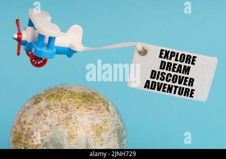Concept de voyage et d'affaires. Sur un fond bleu, un globe et un avion avec un signe - Explorer le rêve découvrir l'aventure. Globe hors foyer. Banque D'Images
