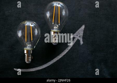 Hausse des prix de l'électricité.ampoule et de l'arrowon sur un tableau noir de craie.coût de l'électricité.crise de la production d'énergie.augmentation du coût de la lumière Banque D'Images