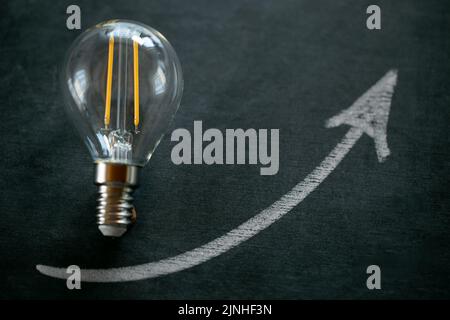 Prix de l'électricité.ampoule et de l'arrowon sur un tableau noir de craie.coût de l'électricité.crise de la production d'énergie.augmentation du coût de la lumière et de la chaleur Banque D'Images