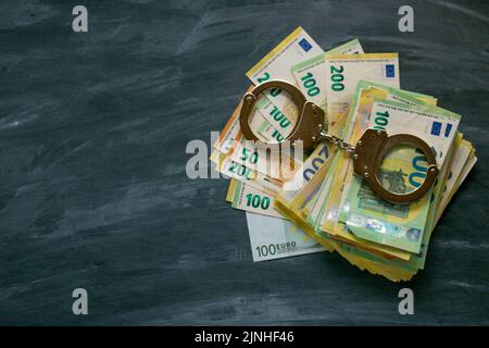 crimes économiques. Corruption et gaspillage du budget dans l'Union européenne.menottes, factures d'euros sur fond de tableau noir.prise de pots-de-vin et sanctions Banque D'Images