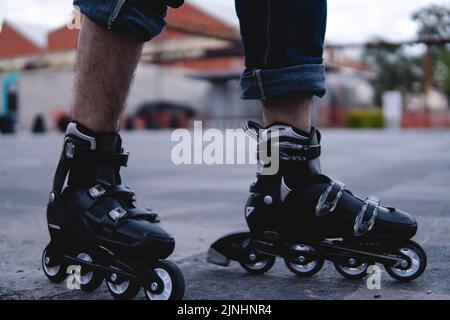 Gros plan d'une paire de patins à roulettes à l'extérieur. Les patins sont noirs et blancs. Pieds avec patins. Photo de haute qualité Banque D'Images