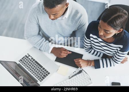 Soyez toujours prêt à apprendre et à essayer dans les affaires. Photo en grand angle de deux jeunes hommes d'affaires qui traversent des chiffres sur un ordinateur portable à leur bureau. Banque D'Images