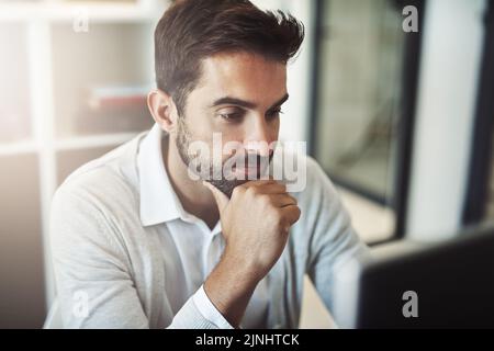 Il envisage la manière la plus intelligente de faire des affaires : un homme d'affaires charmant travaillant sur son ordinateur. Banque D'Images